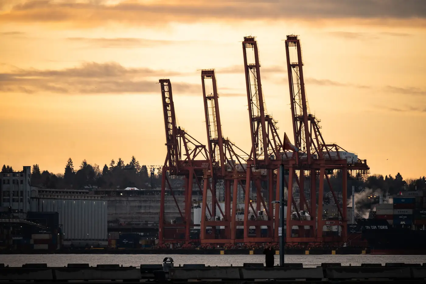 A ship-to-shore crane silhouetted against the sky at a harbor in the evening.